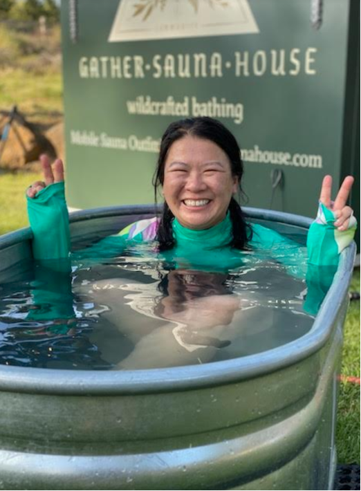 a smiling woman in a green shirt in a cold plunge pool